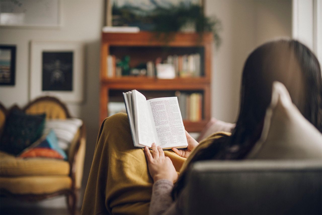 Uma menina lê o Livro de Mórmon no sofá