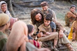 Jesus Cristo sentado no chão com uma criança ensina Seus seguidores a se tornarem como criancinhas