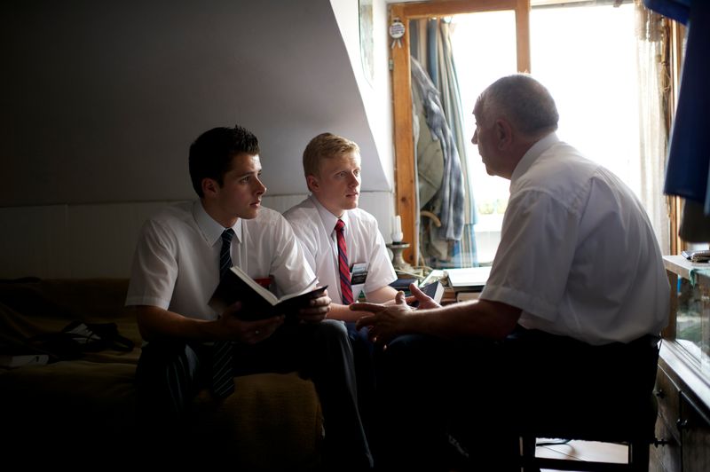 Dois missionários sentados com um senhor e conversando sobre o evangelho de Jesus Cristo e a Bíblia