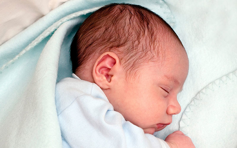 Um recém-nascido adormecido envolto em um cobertor