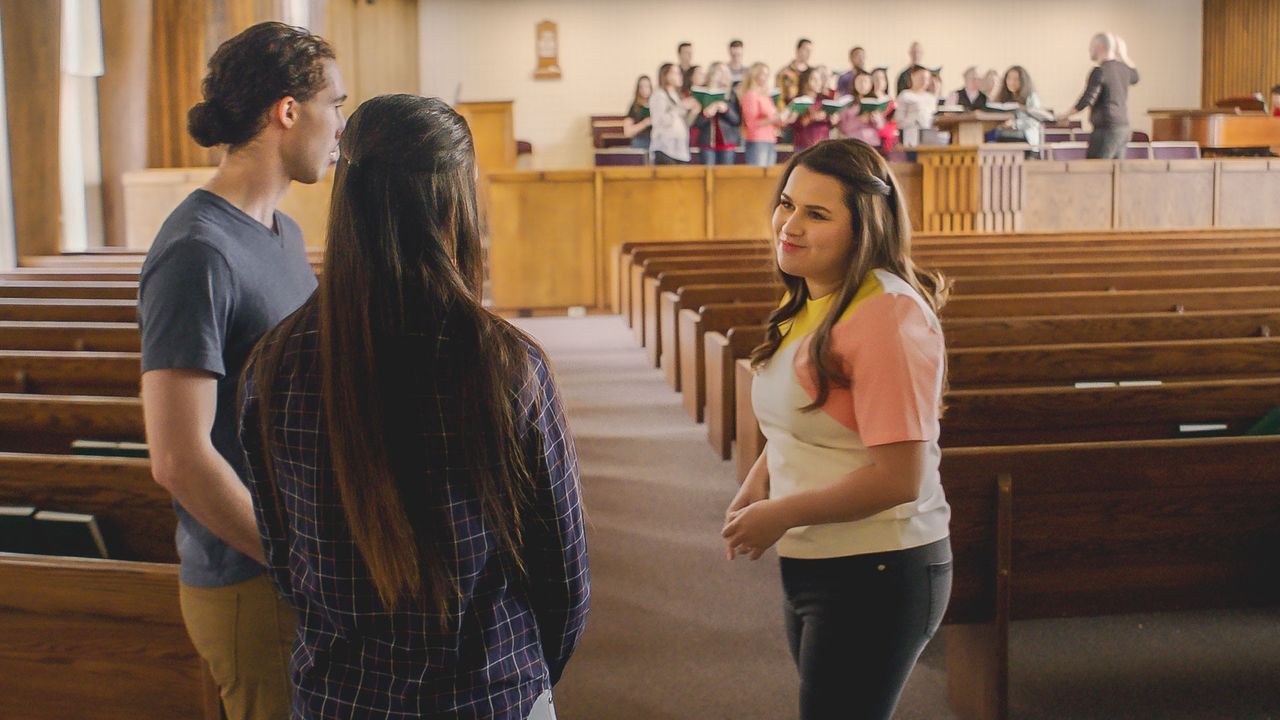 Uma mulher apresenta o edifício da Igreja para um casal