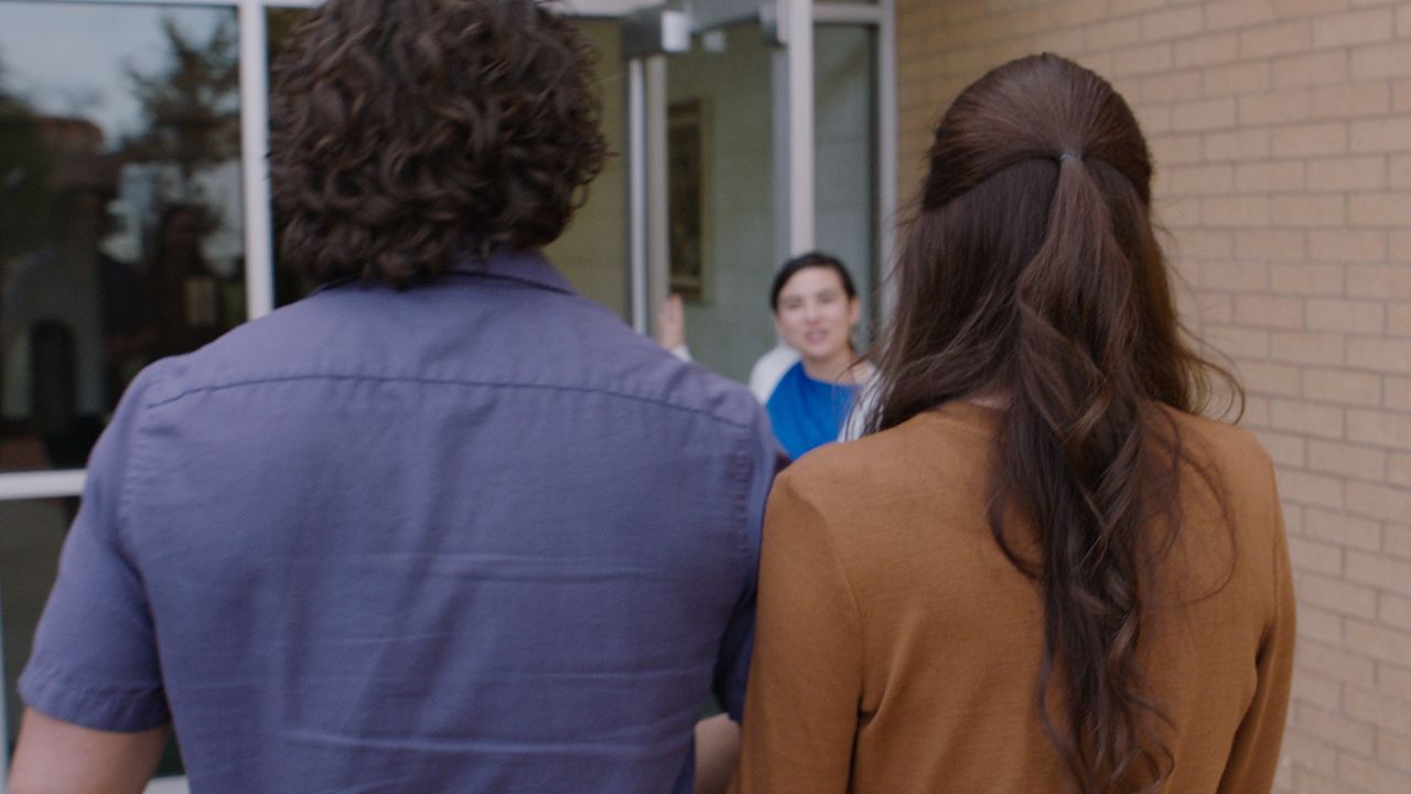 Um casal é recebido na porta por alguém que guardou um lugar para eles na igreja