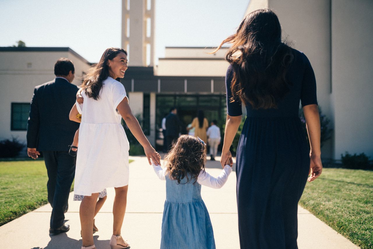 Uma garotinha pega a mão de uma mulher ao entrar na capela da igreja